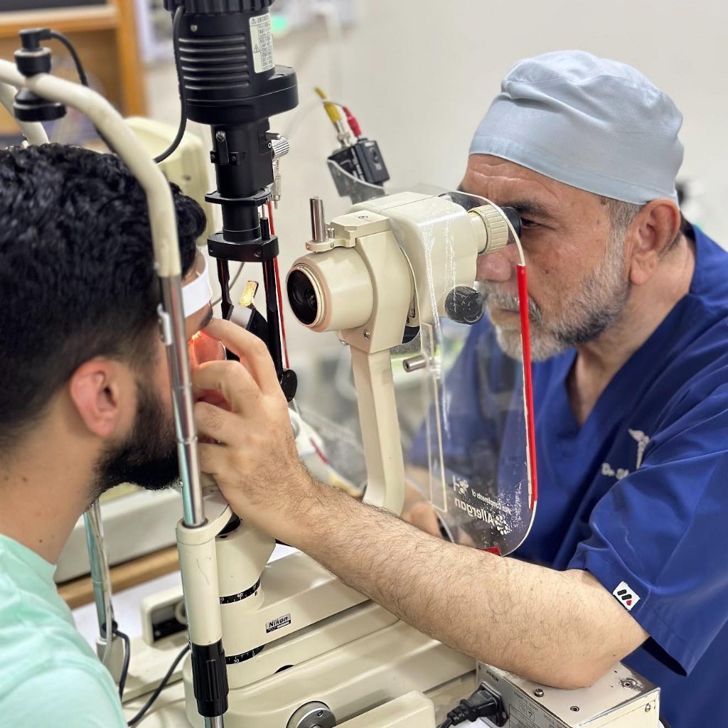 Ophthalmologist examining a patient at a professional slit lamp with protective breath shield
